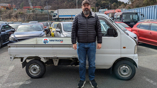 A tall person standing in front of a Suzuki Carry Truck